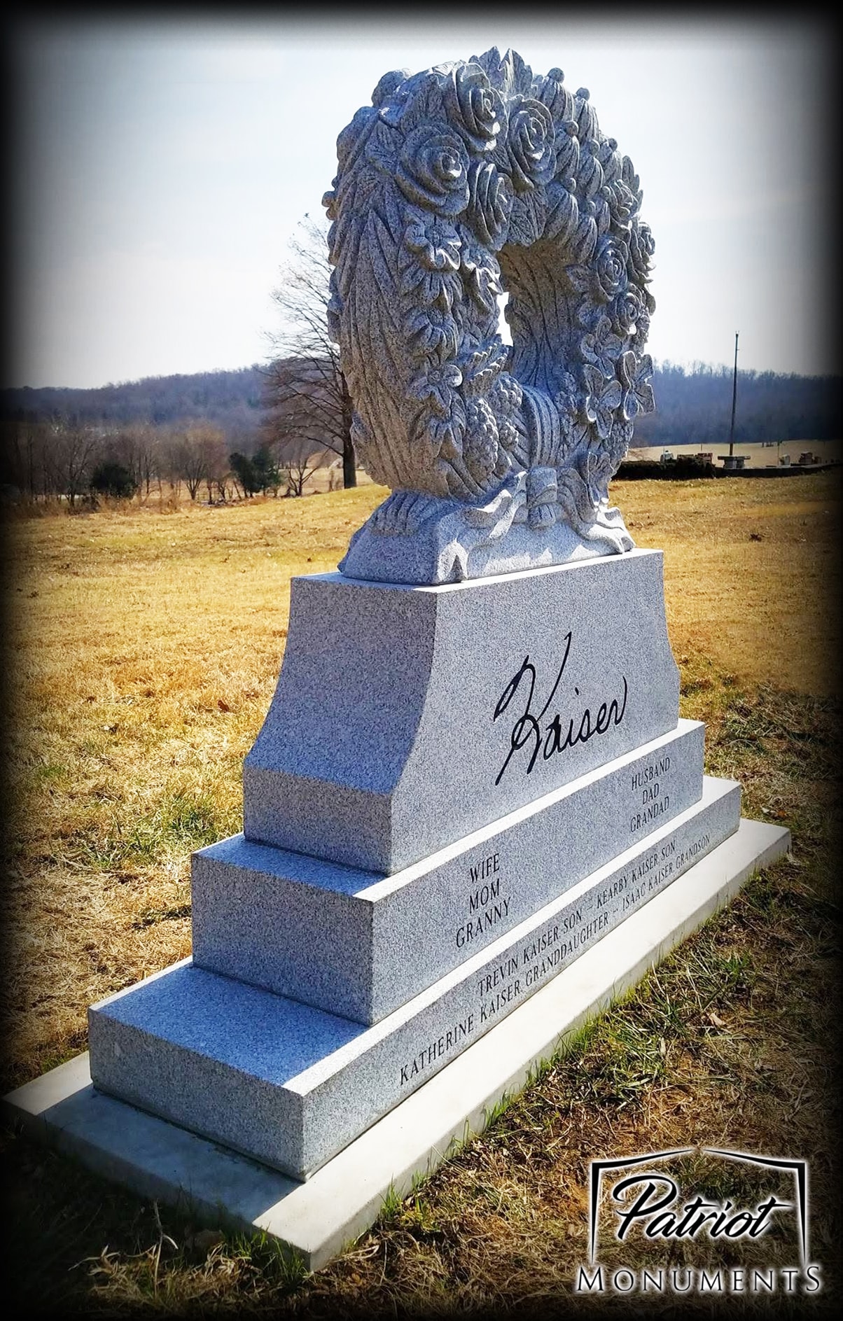 Kaiser gray granite monument with ornate carved floral wreath topper